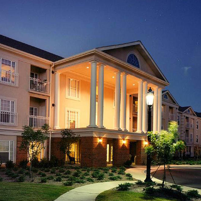 Outside of a Brookdale location, a large building with stunning columns and a   manicured  lawn.